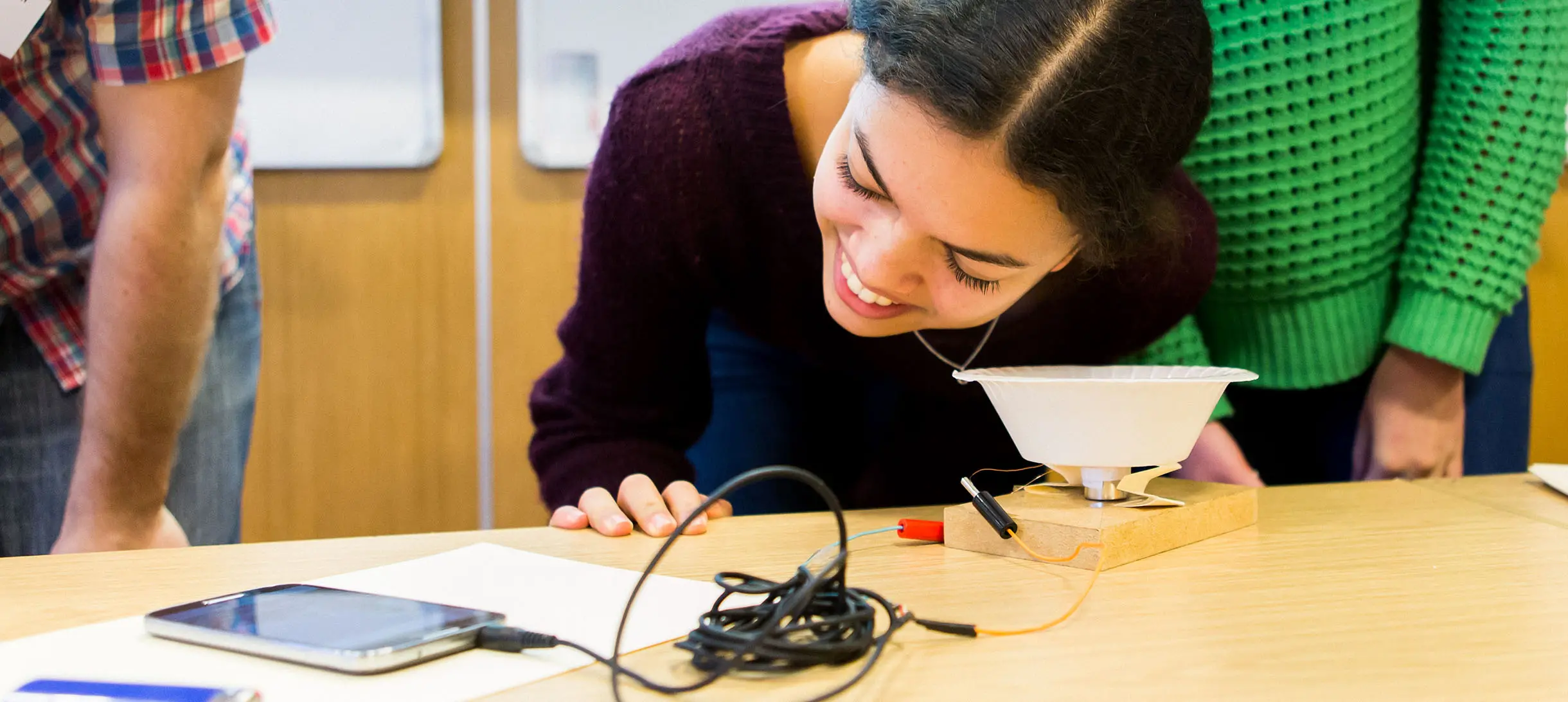 young woman looks at a jumble of wires and electronic parts