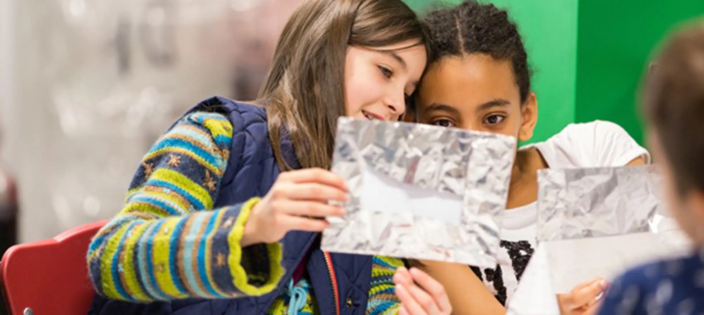 two girls looking at a piece of crumbled up aluminium foil