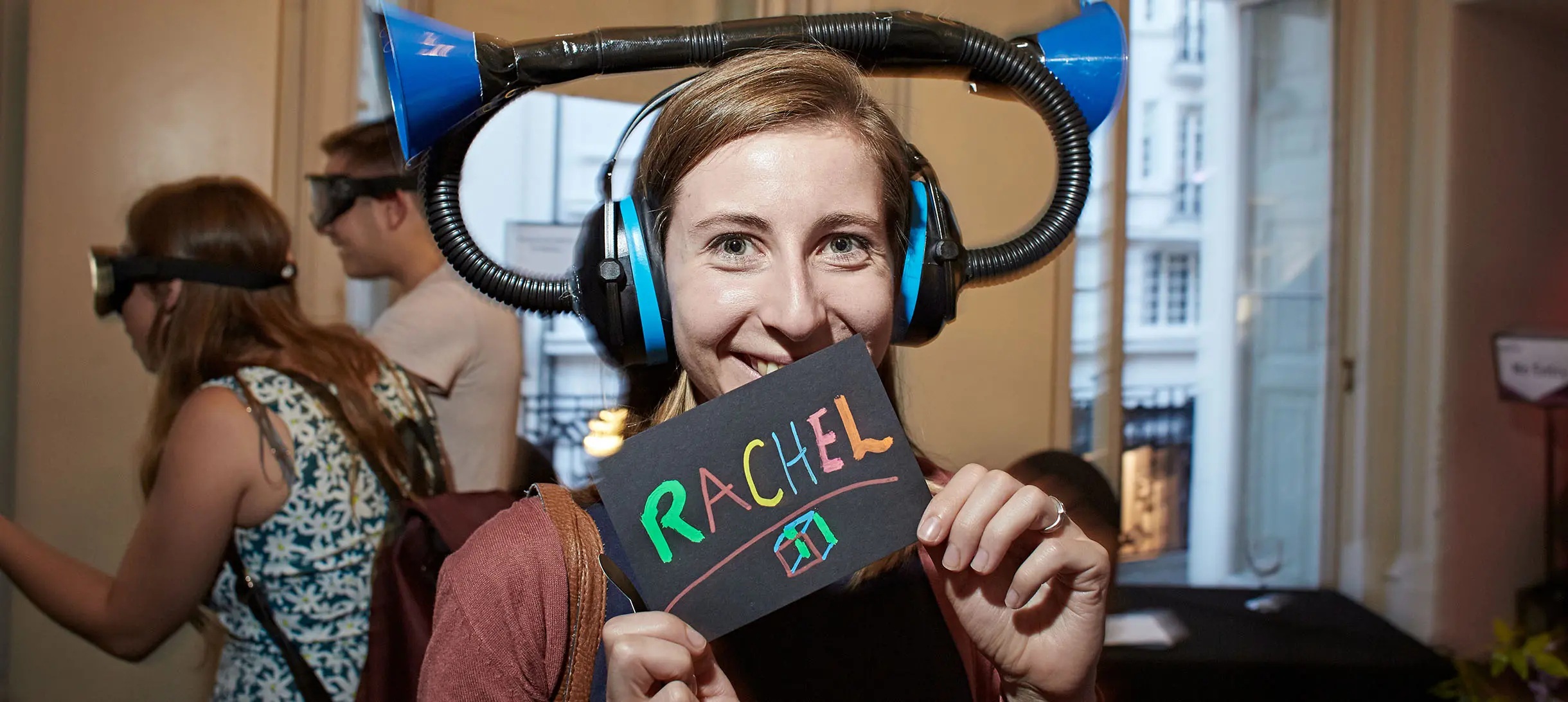 a woman with a trumpet like hat on her head holding a sign that says "Rachel"