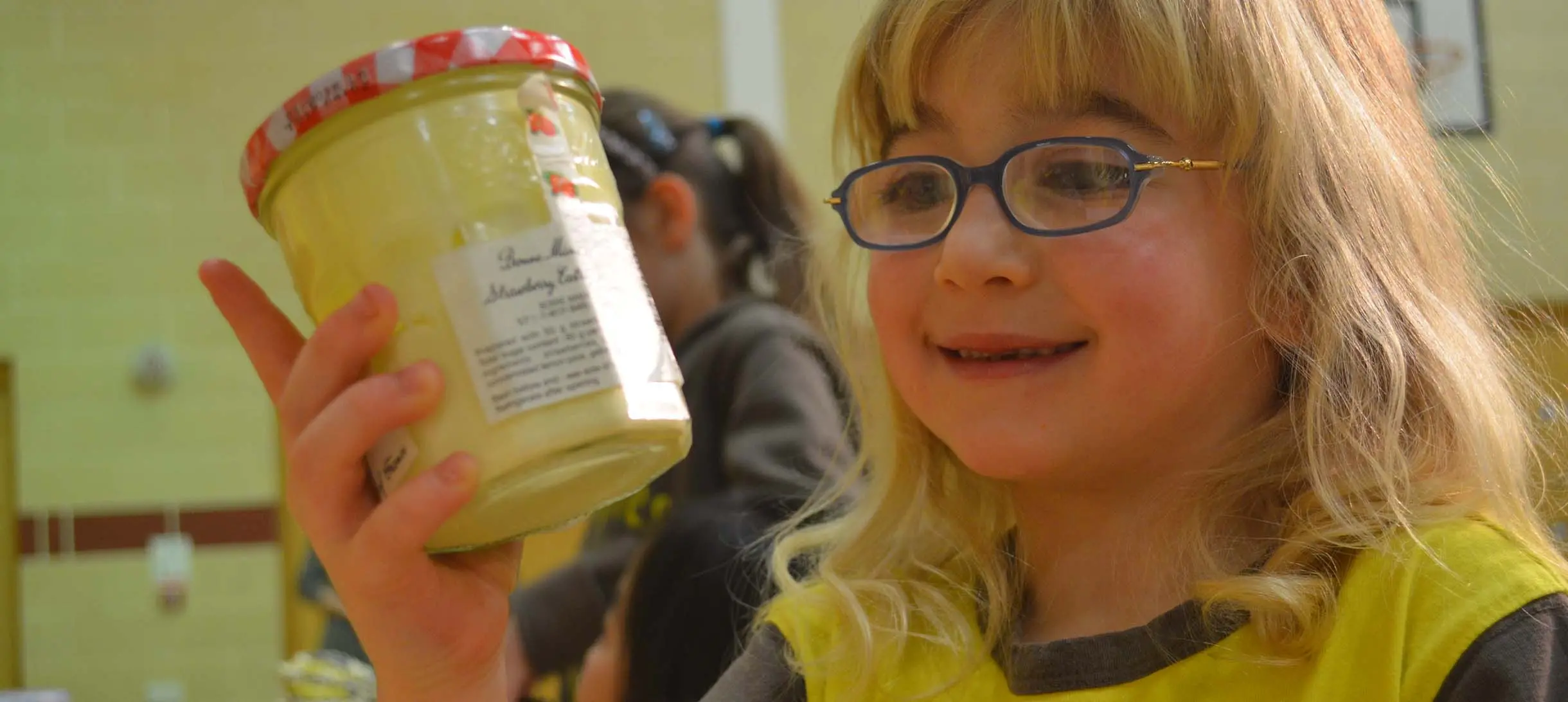 a young girl with glasses is looking at a jar of cream
