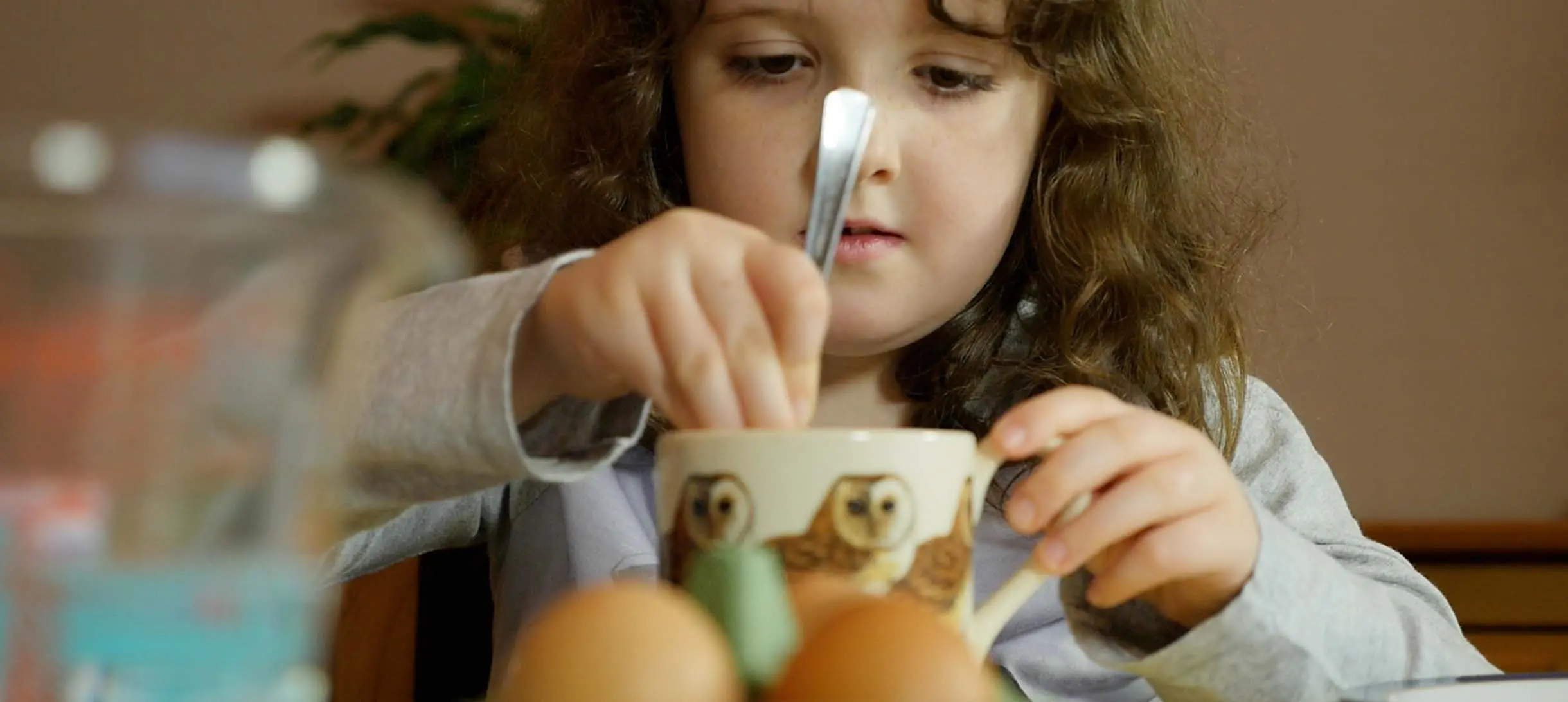 a girl stirs something in a cup with a spoon
