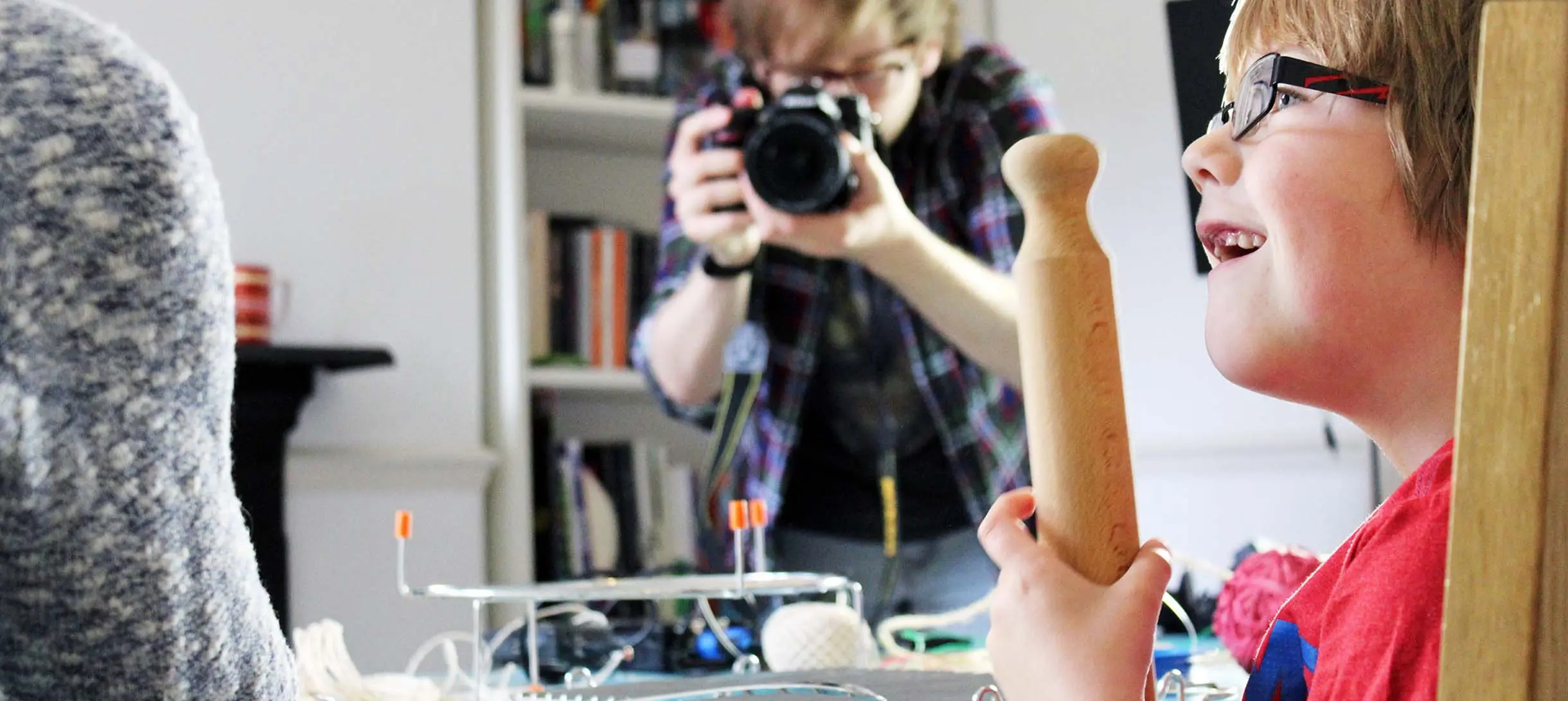 Small boy looking amazed at a science experiment while a photographer is capturing the moment in the background