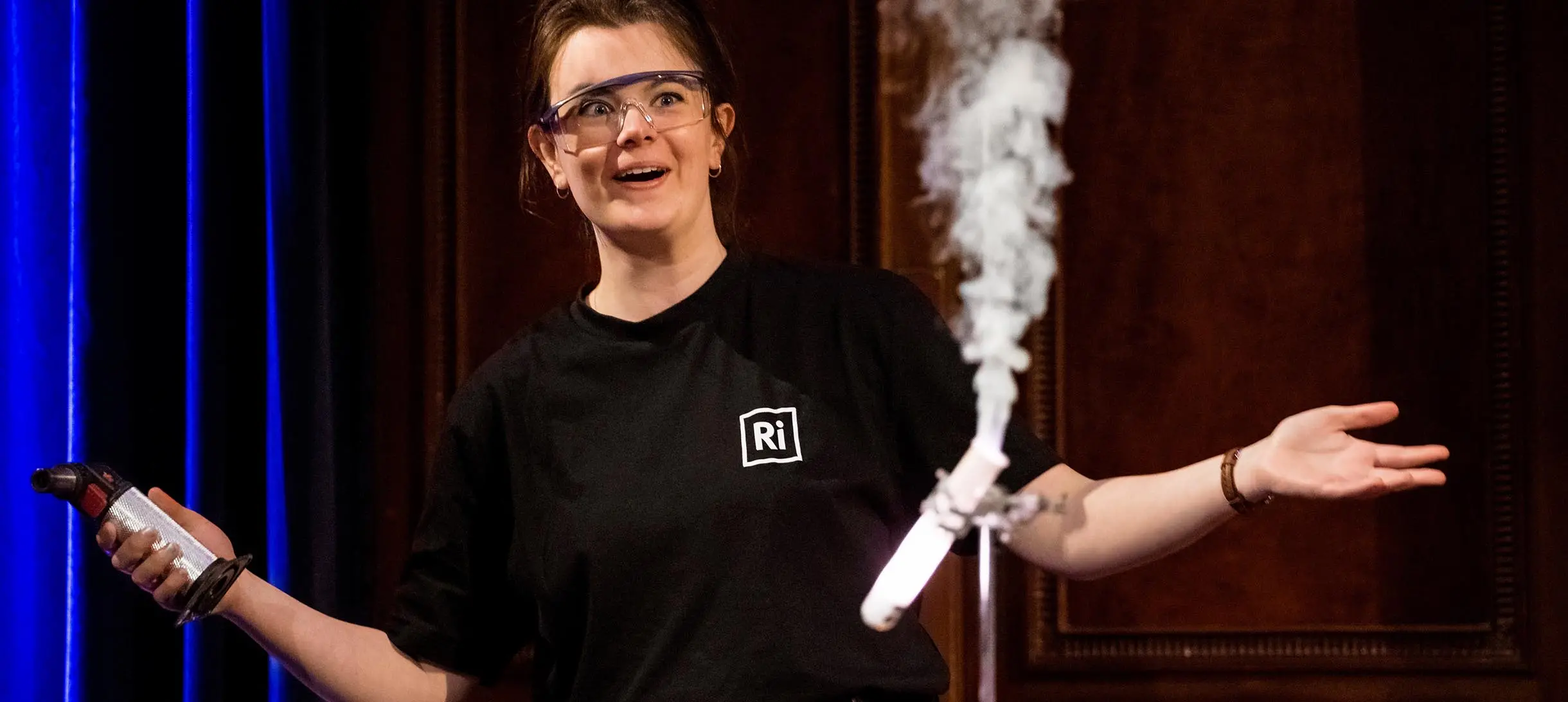 a woman with her arms spread wide and and a test tube with smoke coming out of it
