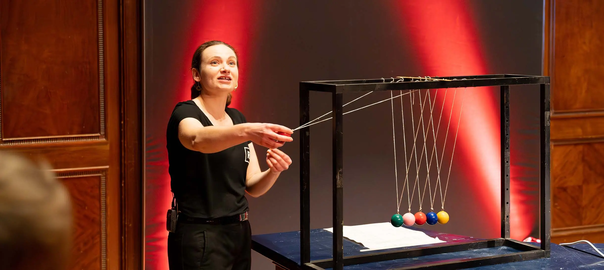 A woman about to activate a Newton's cradle with colourful balls