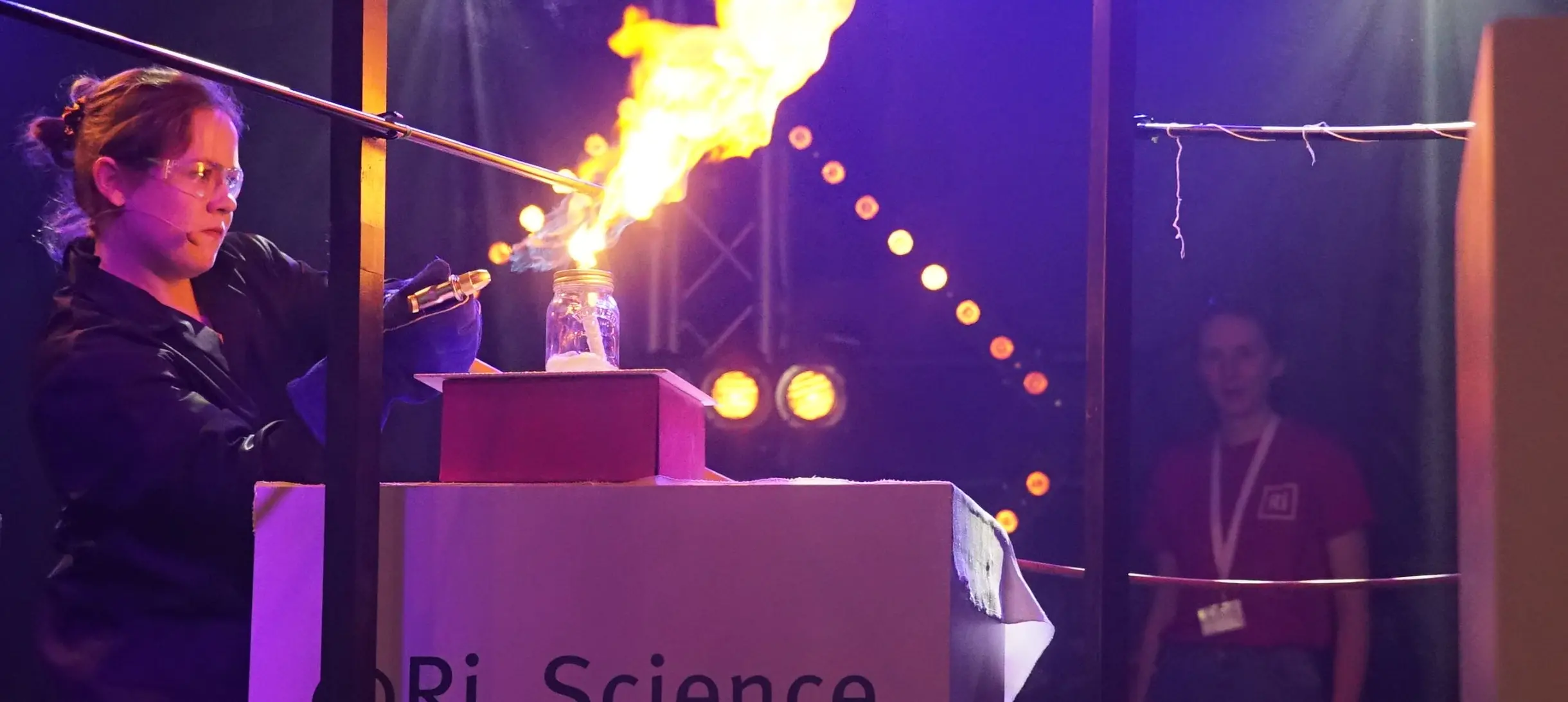 A female scientist demonstrating a fiery explosion at the Ri
