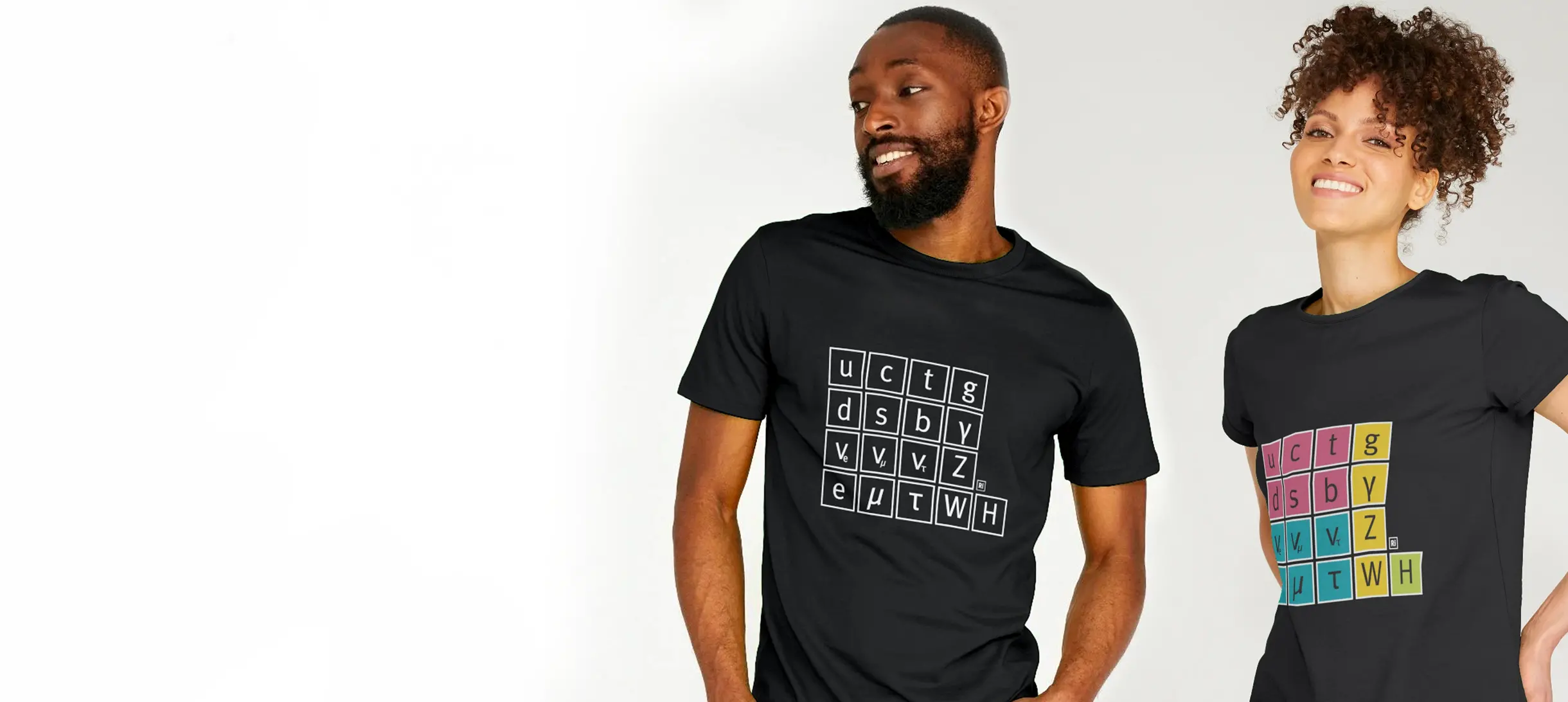 A man is wearing a black T-shirt with a white drawing of the standard model on it, a woman is next to him weaing a black t-shirt with a colourful graphic of a standard model on it