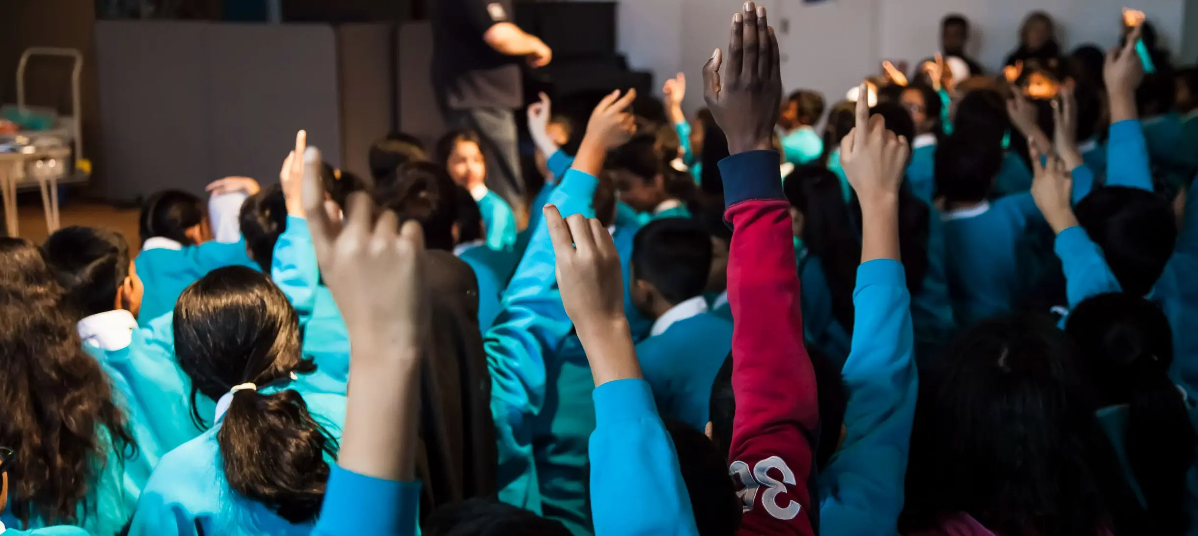 Children's hands go up in a science in schools presentation