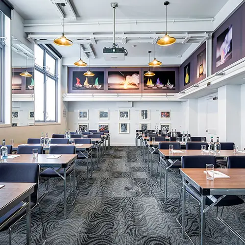 a large plain white room, with trestle tables set up like a classroom