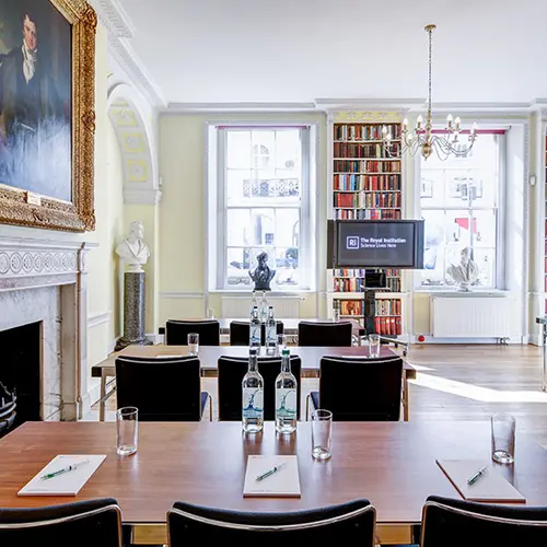 a bright small room with desks and chairs lined up to face a TV screen