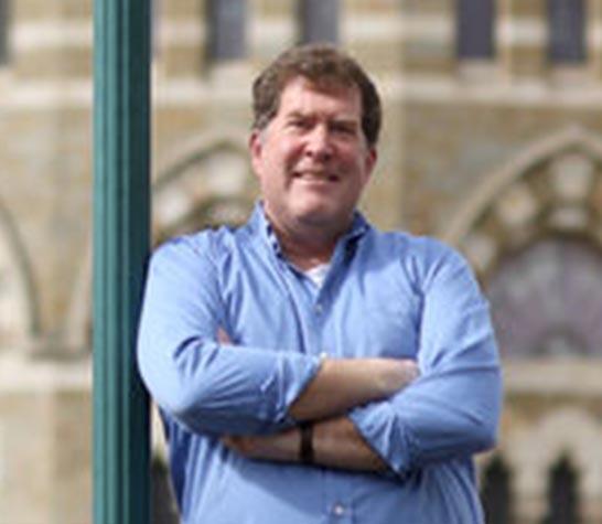 man in blue button up shirt with his arms crossed across his chest