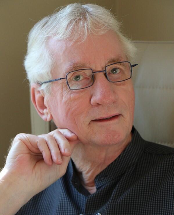 A man with grey hair looking at camera with a side profile.