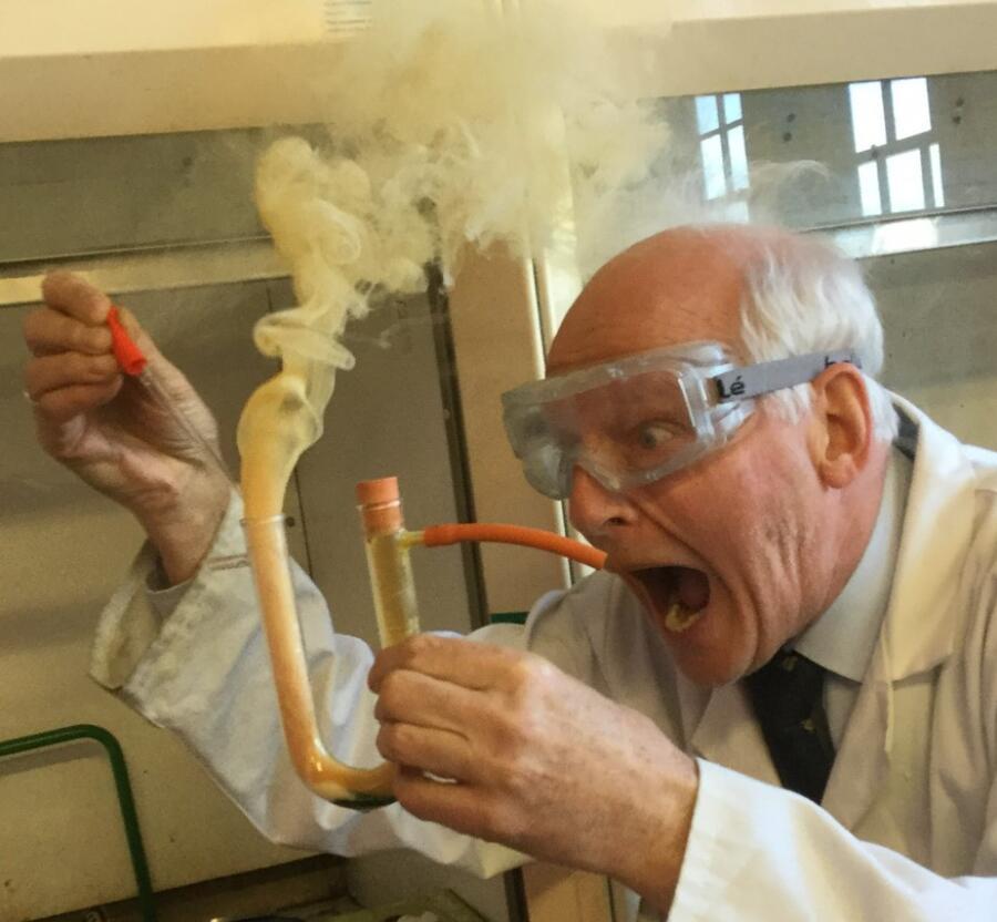 A chemist holds a smoking glass aparatus