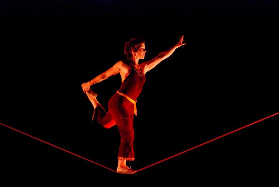 A woman is balancing on one leg on a tightrope.