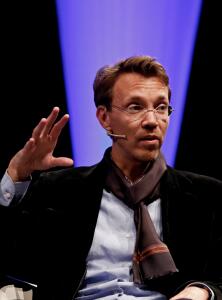 Rudolph Herzog is speaking with a microphone heatseat. He is talking to an audience.