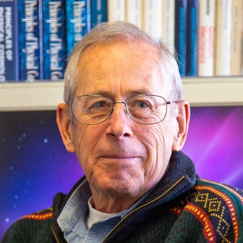 A man is looking towards the camera. He is wearing glasses.