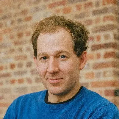 Hnery is looking at the camera, waering a blue jumper.