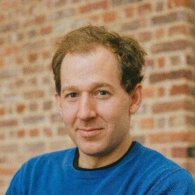 Hnery is looking at the camera, waering a blue jumper.