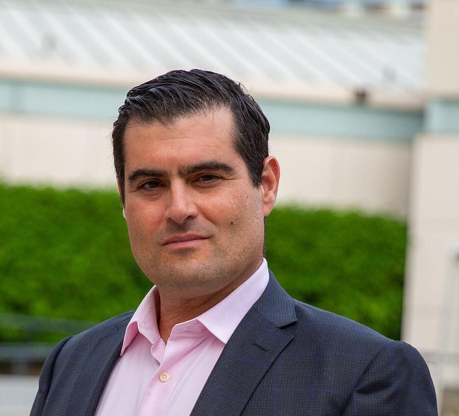 A man is looking towards the camera. He has short black hair.