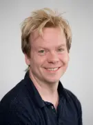 a man is smiling at the camera. He has short blonde hair.