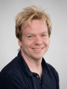 a man is smiling at the camera. He has short blonde hair.
