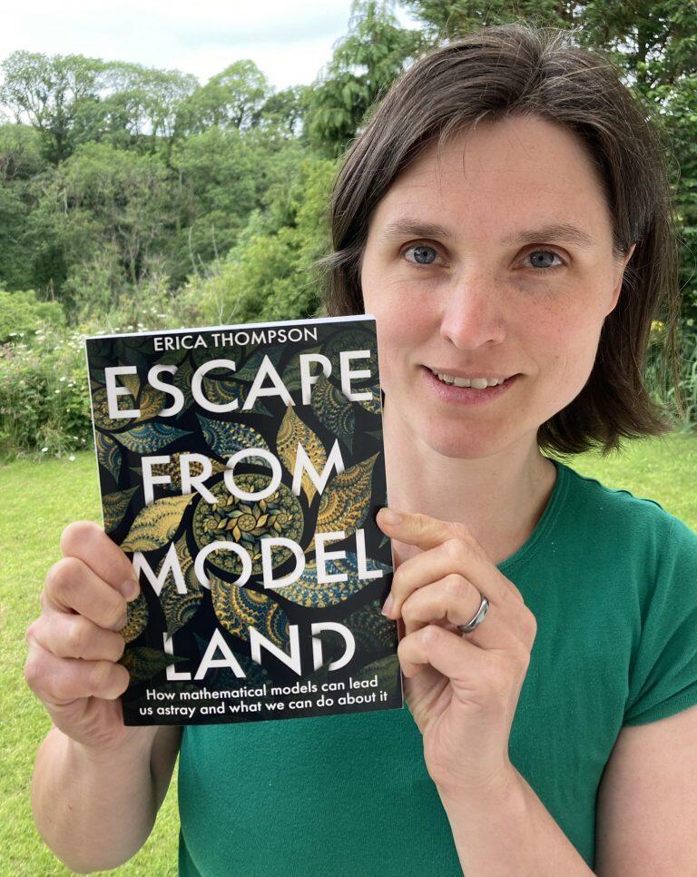 A picture of a woman with short brown hair is holding up a book that says 'Escape from model land'.