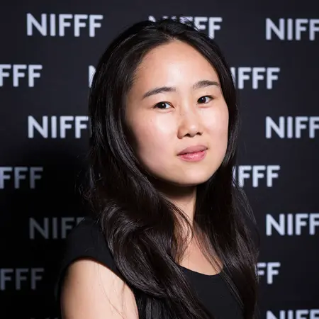 A woman is looking at the camera, side profile. She has long dark hair.