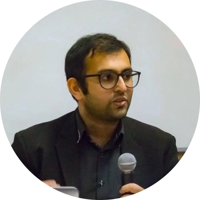 the side profile of a man with glasses who is talking into a microphone.