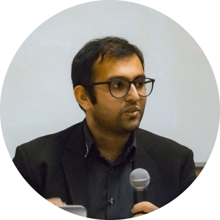 the side profile of a man with glasses who is talking into a microphone.
