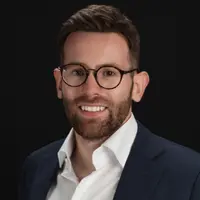 A man with glasses is smiling at the camera
