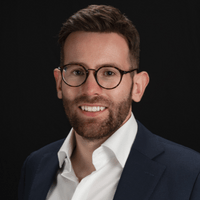 A man with glasses is smiling at the camera