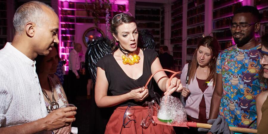 A lively evening event at the Ri. A presenter shows a bubbling chemistry demonstration.