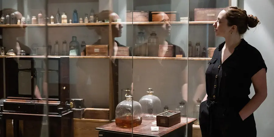 A young woman looking through the glass into Faraday's laboratory