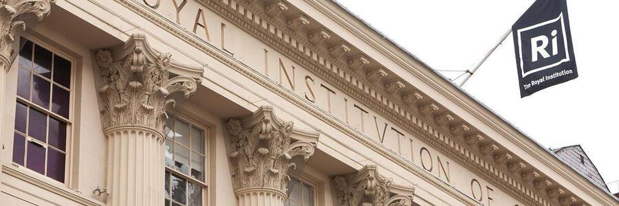 Exterior of the Ri building showing ornate columns and a branded flag