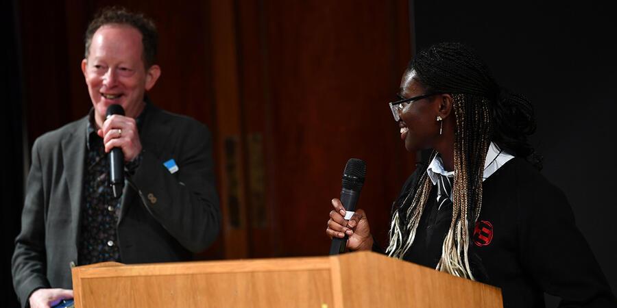 The Ri's Dr Daniel Glaser stands behind a lectern, introducing the young winner