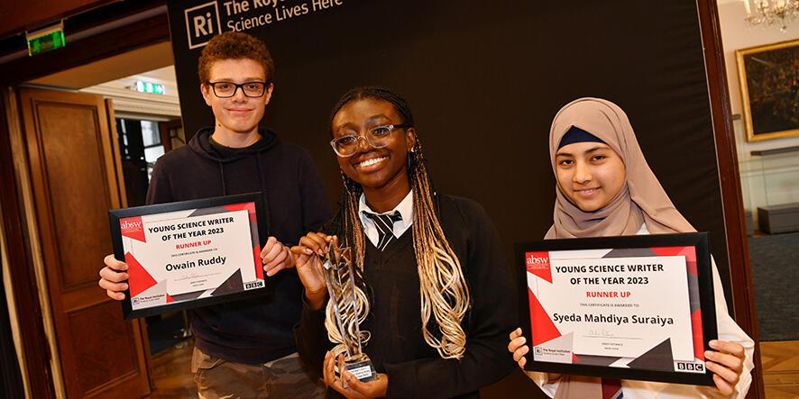 The winner of the competition stands in between the runners up. They are proudly holding up their prizes