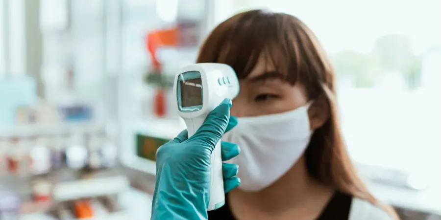 Infrared thermometer being held up to forehead of patient