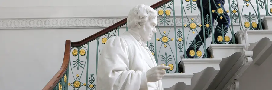 The Faraday statue in the grand entrance of the Ri. We can see a person climbing the stairs next to it