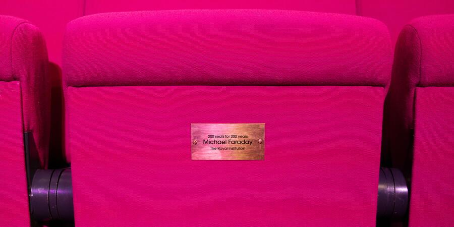 The iconic magenta seats of the Ri Theatre, with a plaque