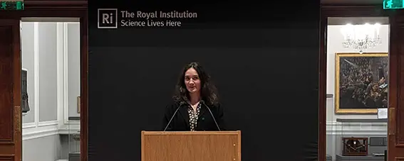Jeanne standing behind a podium in the Ri theatre