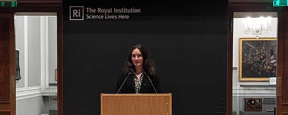 Jeanne standing behind a podium in the Ri theatre