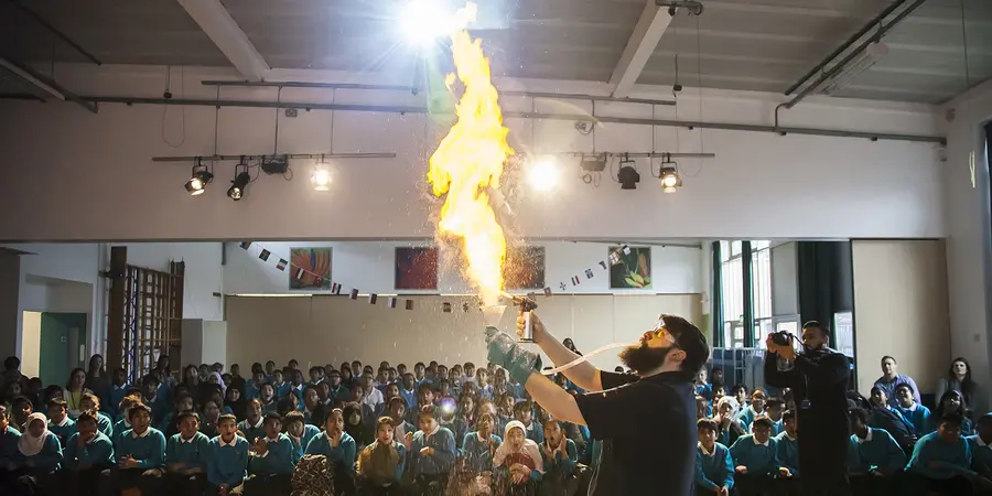A man performing a demonstration with a tall wide flame