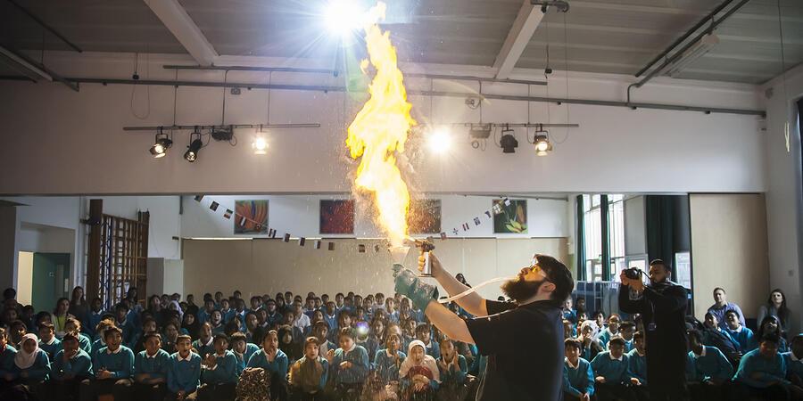 A man performing a demonstration with a tall wide flame