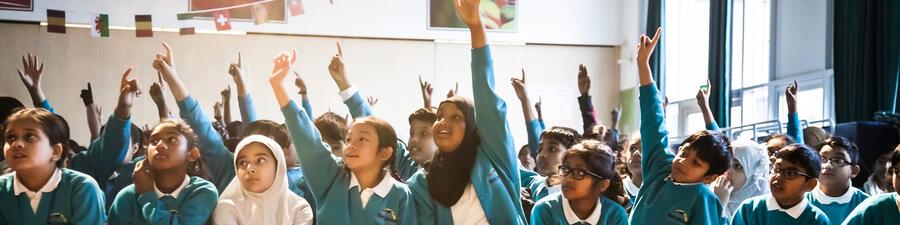 Children raising their hands to participate in a demo during a school visit