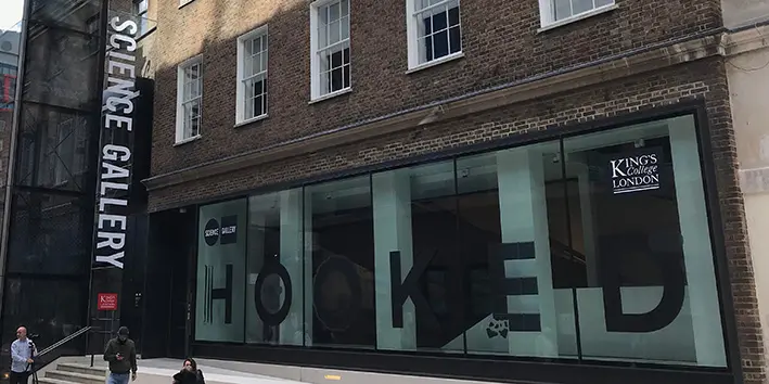 Exterior of the Science Gallery at King's College, showing a large vertical sign with their name, and a red brick facade