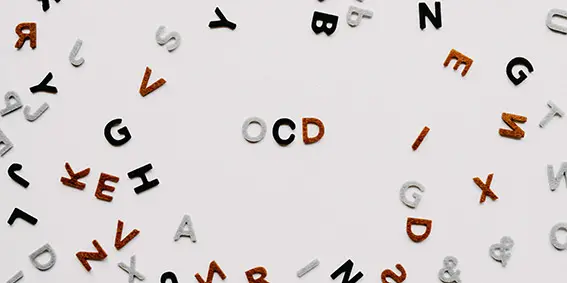 Plastic letters scattered on a surface. In the middle there is a clear area with only the letters OCD