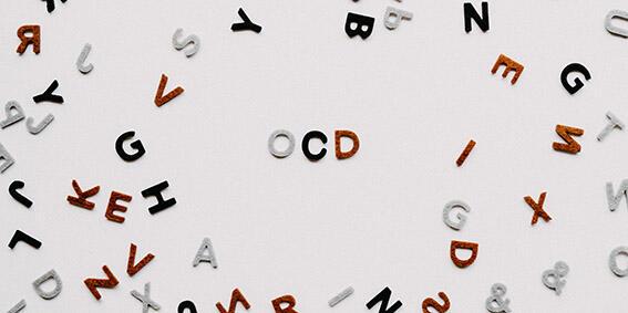 Plastic letters scattered on a surface. In the middle there is a clear area with only the letters OCD