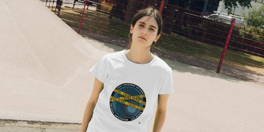 A woman wearing a white tshirt with the Christmas Lectures design, featuring a fingerprint and police tape
