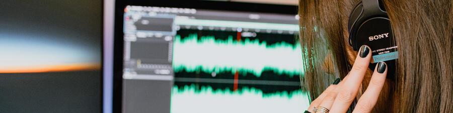 A person wearing headphones, using audio editing software