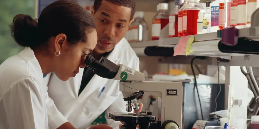 Researchers looking into a microscope.