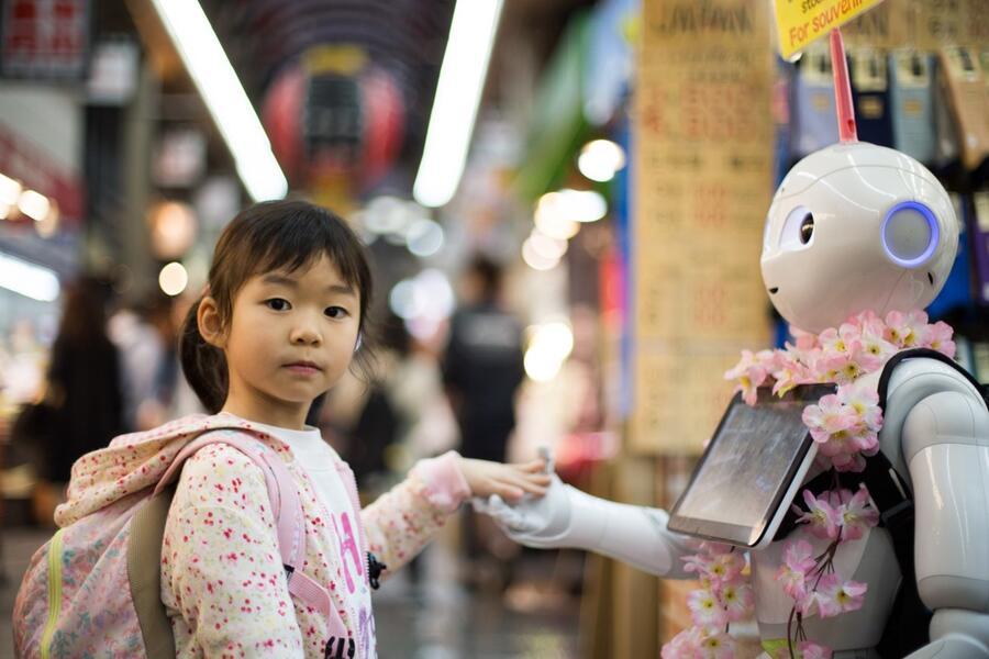 A child holding the hand of a humanoid robot